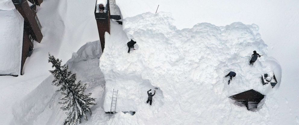 PHOTO: Workers remove snow from the roof of a condominium complex in the Sierra Nevada mountains, after yet another storm system brought heavy snowfall, March 29, 2023, in Mammoth Lakes, Calif.