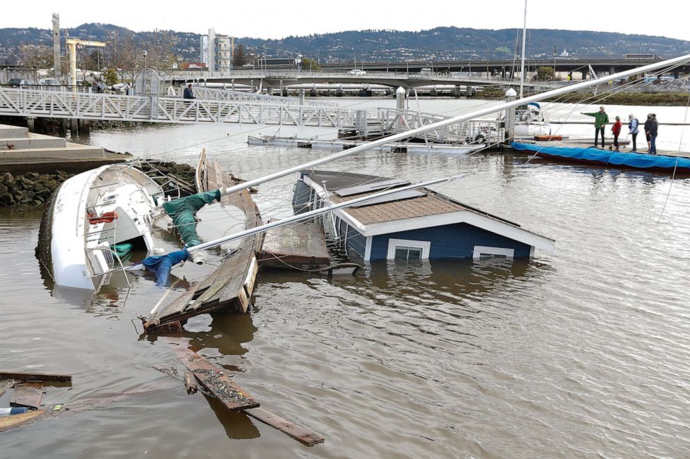 PHOTO: People work to pump water out of a boat, near a submerged boat and houseboat at Jack London Aquatic Center, March 22, 2023, in Oakland, Calif.