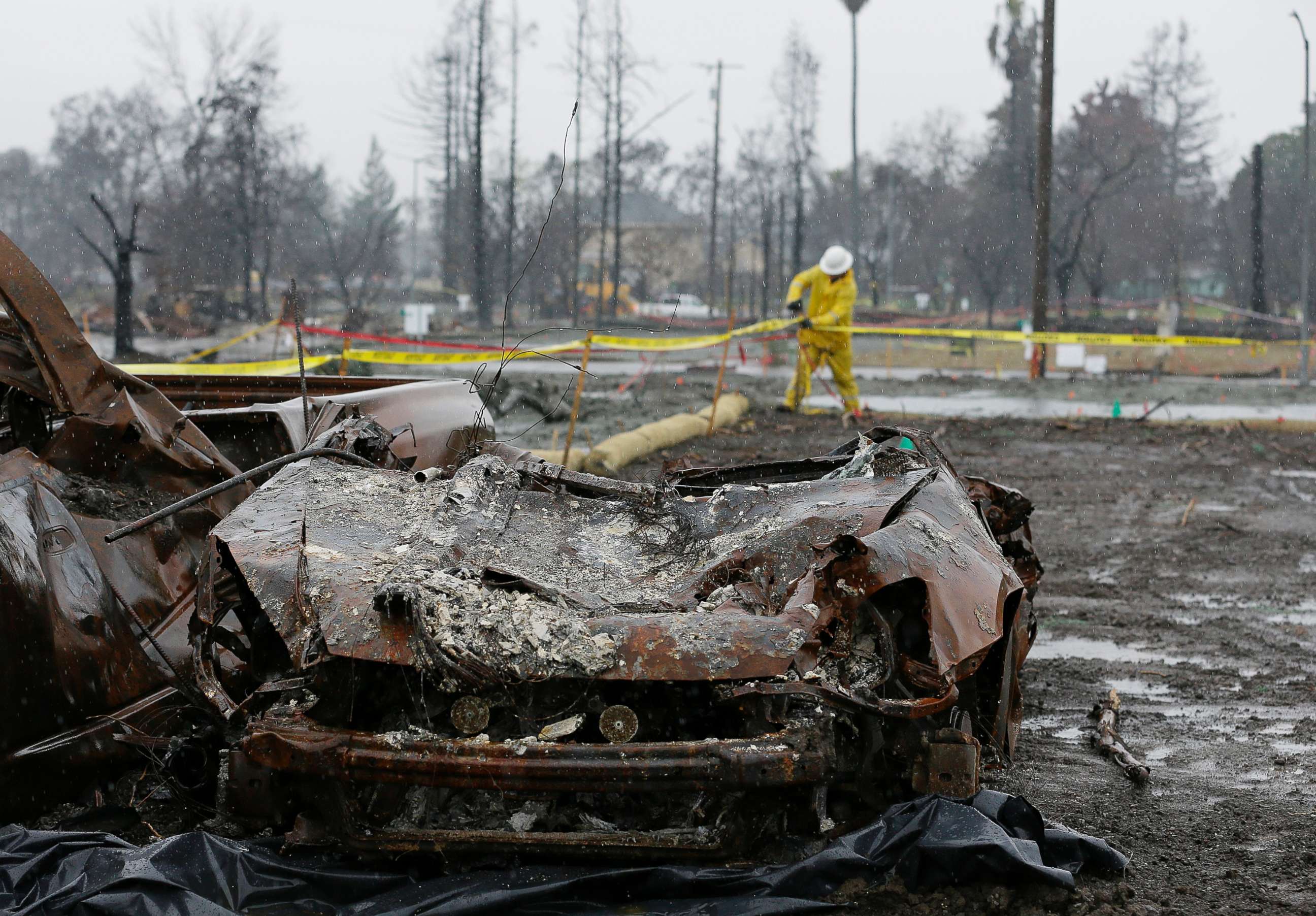 PHOTO: With a burned car in the foreground a worker finishes up erosion control efforts in the wildfire damaged Coffey Park neighborhood, Jan. 8, 2018, in Santa Rosa, Calif. 