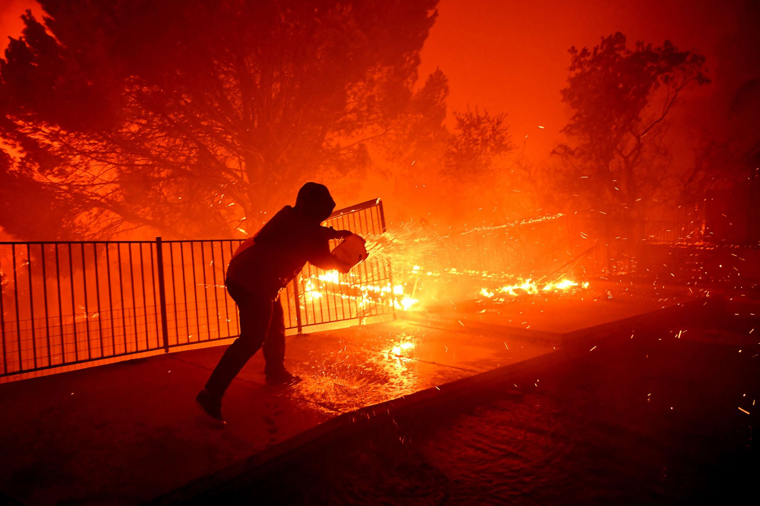 PHOTO: Ozzy Butler pours water on to his deck at his parents house as the Saddleridge Fire burns along Thunderbird Ave. in Porter Ranch, Calif., Oct. 11, 2019.
