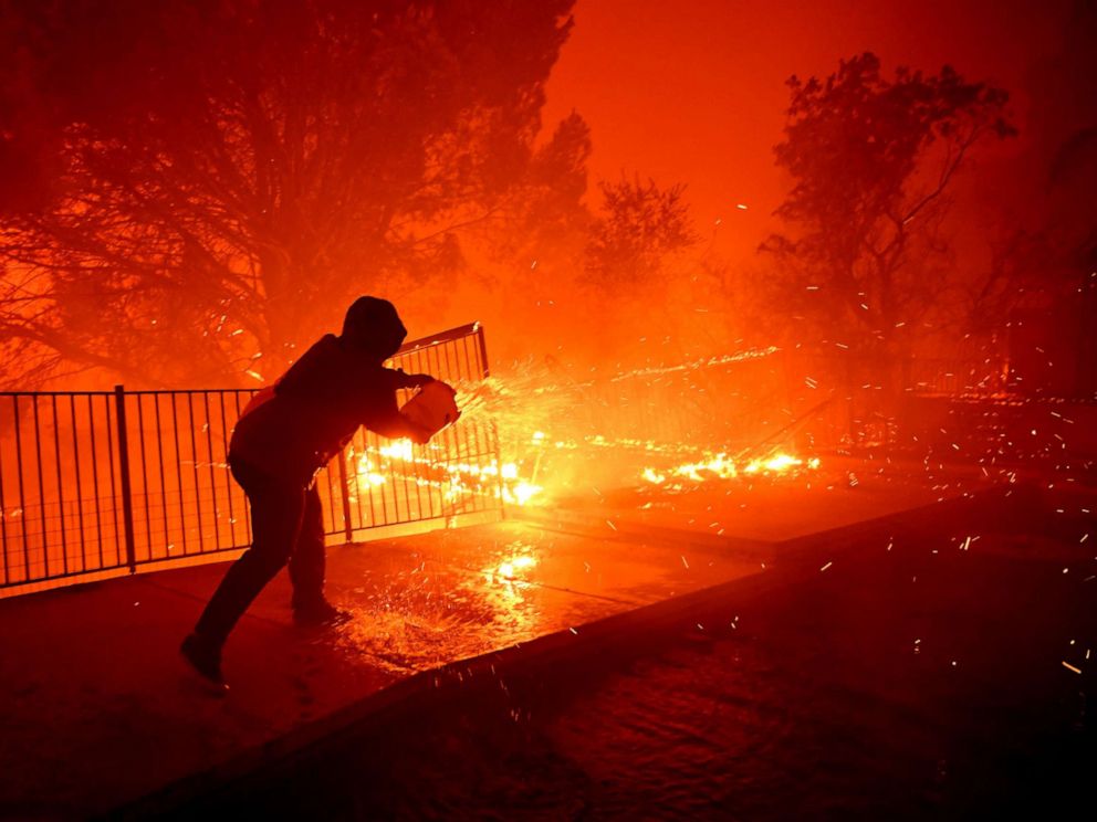 PHOTO: Ozzy Butler pours water on to his deck at his parents house as the Saddleridge Fire burns along Thunderbird Ave. in Porter Ranch, Calif., Oct. 11, 2019.