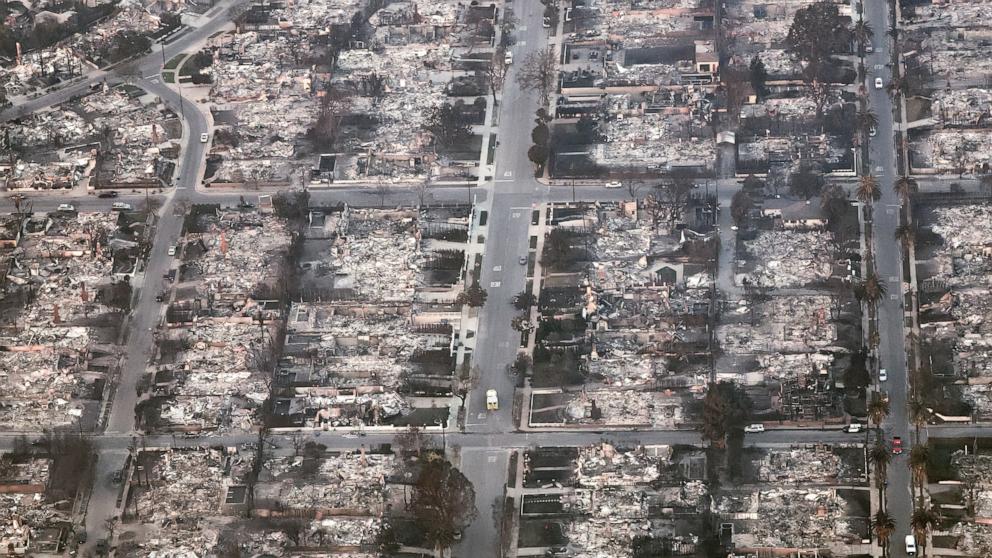 PHOTO: An aerial view of an emergency vehicle (C) driving past destroyed homes as the Palisades Fire continues to burn on Jan. 9, 2025 in Pacific Palisades, Calif.