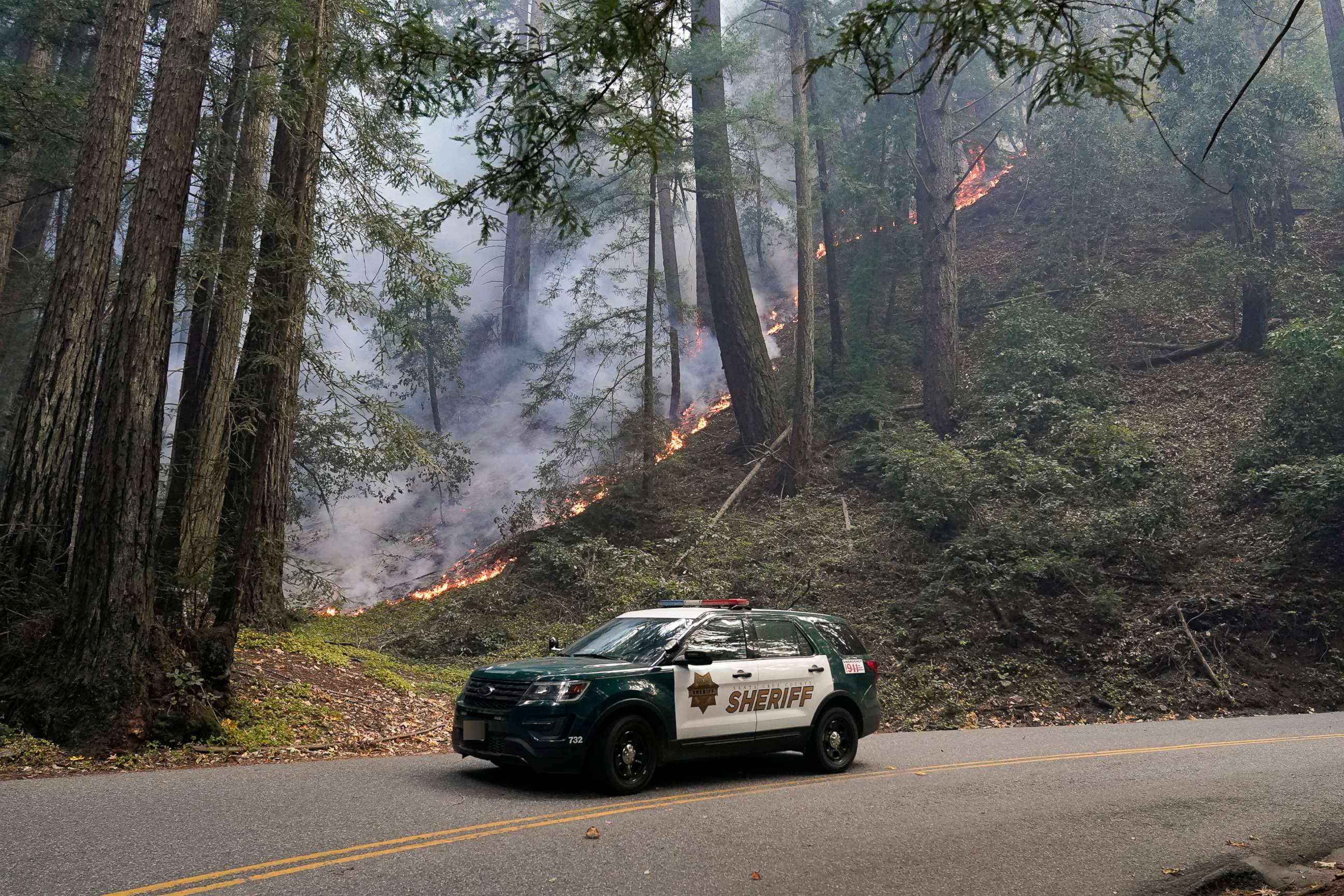 PHOTO: A police vehicle is seen under a forest being burned by the CZU August Lightning Complex Fire, Aug. 24, 2020, in Bonny Doon, Calif.