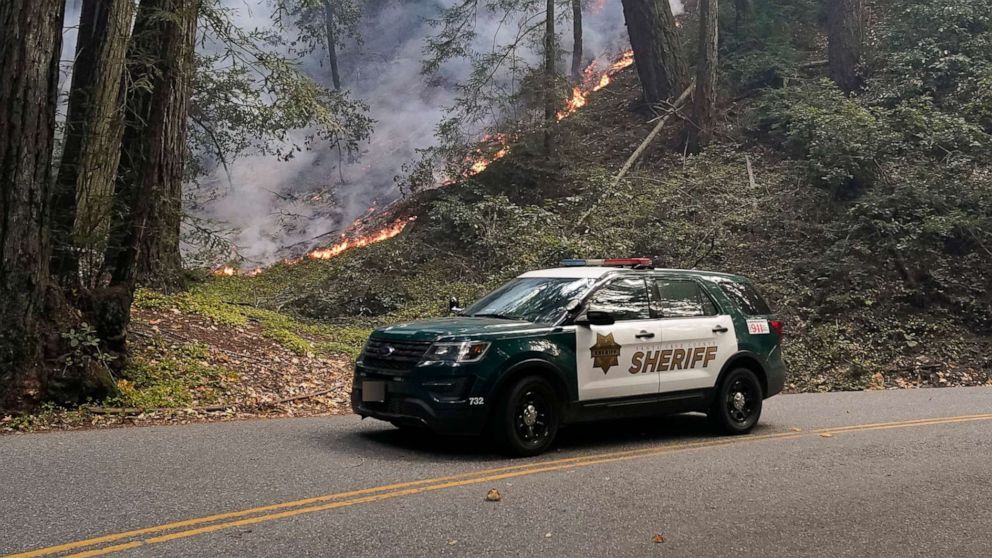 PHOTO: A police vehicle is seen under a forest being burned by the CZU August Lightning Complex Fire, Aug. 24, 2020, in Bonny Doon, Calif.