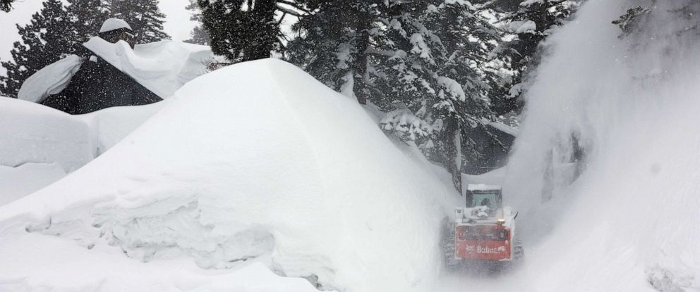 PHOTO: A snowblower clears a driveway in the Sierra Nevada mountains, near snowbanks piled up from new and past storms, after yet another storm system brought heavy snowfall further raising the snowpack, March 29, 2023, in Mammoth Lakes, Calif.