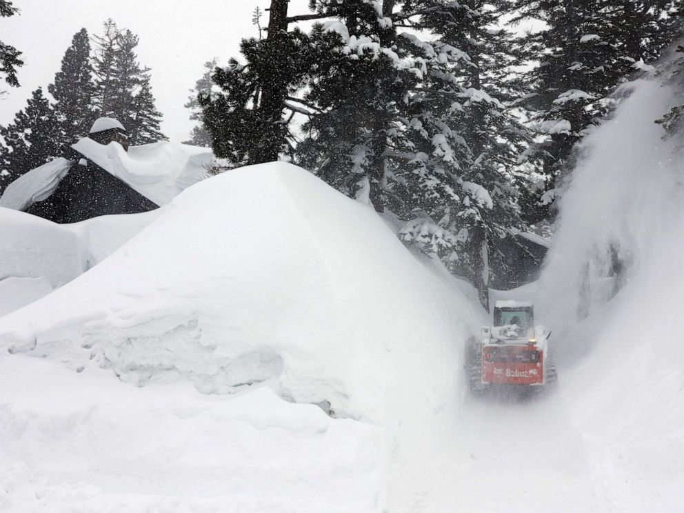 PHOTO: A snowblower clears a driveway in the Sierra Nevada mountains, near snowbanks piled up from new and past storms, after yet another storm system brought heavy snowfall further raising the snowpack, March 29, 2023, in Mammoth Lakes, Calif.