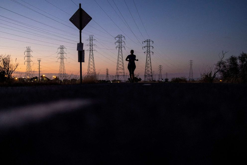 PHOTO: A woman jogs by power lines as a wave of extreme heat settled over much of California, in Mountain View, Calif., Aug. 17, 2022. 