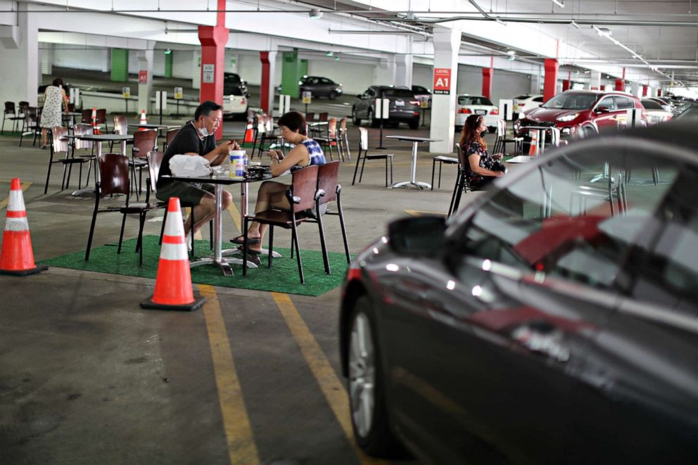 PHOTO: People eat lunch in a dining area set up in the Glendale Galleria mall parking garage in Glendale, Calif., July 31, 2020.