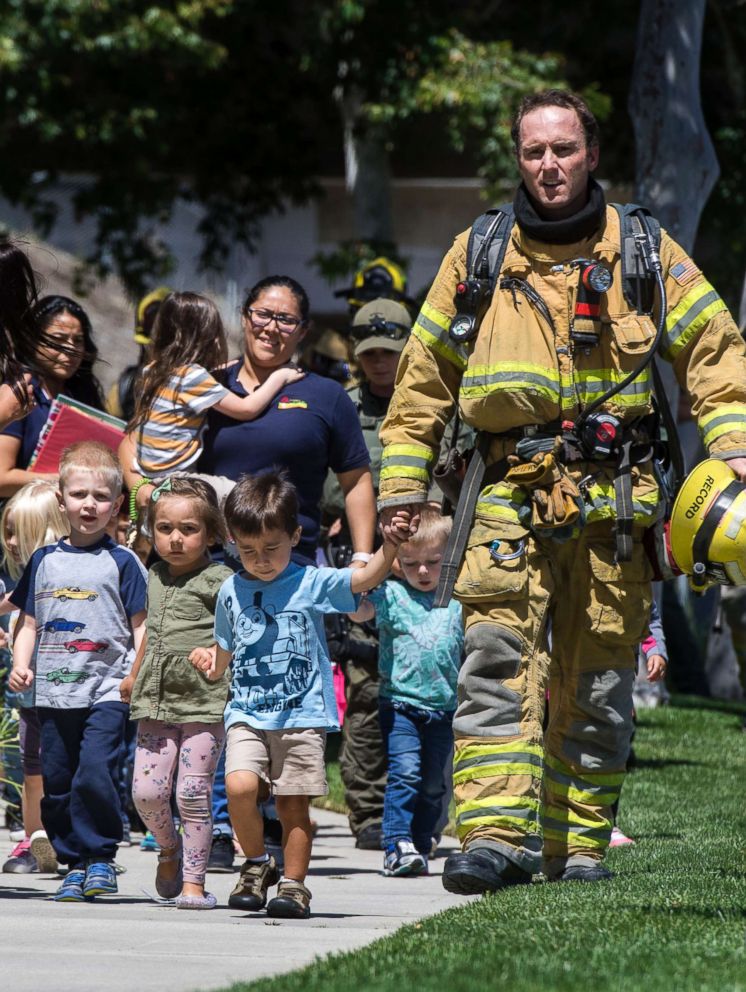 PHOTO: Firefighters and sheriff's deputies escort children from Academy on the Hill pre-k school in Aliso Viejo, Calif., May 15, 2018, after a fatal explosion nearby.