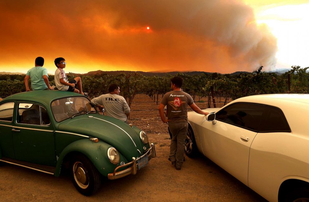 PHOTO: Local residents sit next to a vineyard as they watch the LNU Lightning Complex fire burning in nearby hills, Aug. 20, 2020, in Healdsburg, California.