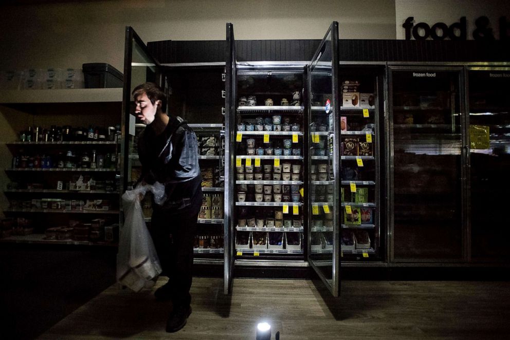 PHOTO: In this Oct. 9, 2019, file photo, CVS Pharmacy shift supervisor James Quinn throws out ice cream from darkened freezers as downtown Sonoma, Calif., remains without power.