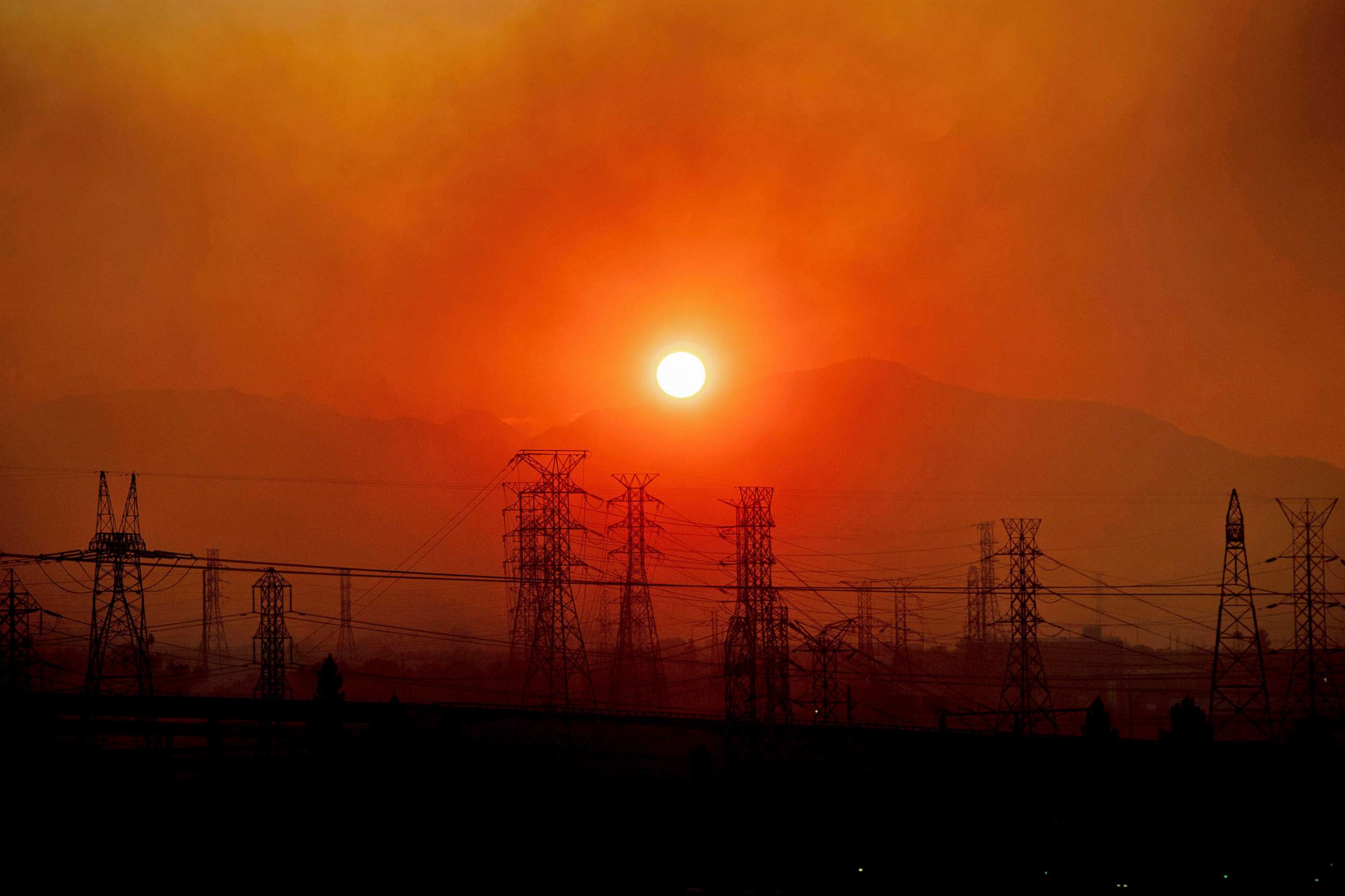 PHOTO: In this Oct. 11, 2019, file photo, smoke from the Saddle Ridge Fire hangs above power lines as the sun rises in Newhall, Calif.