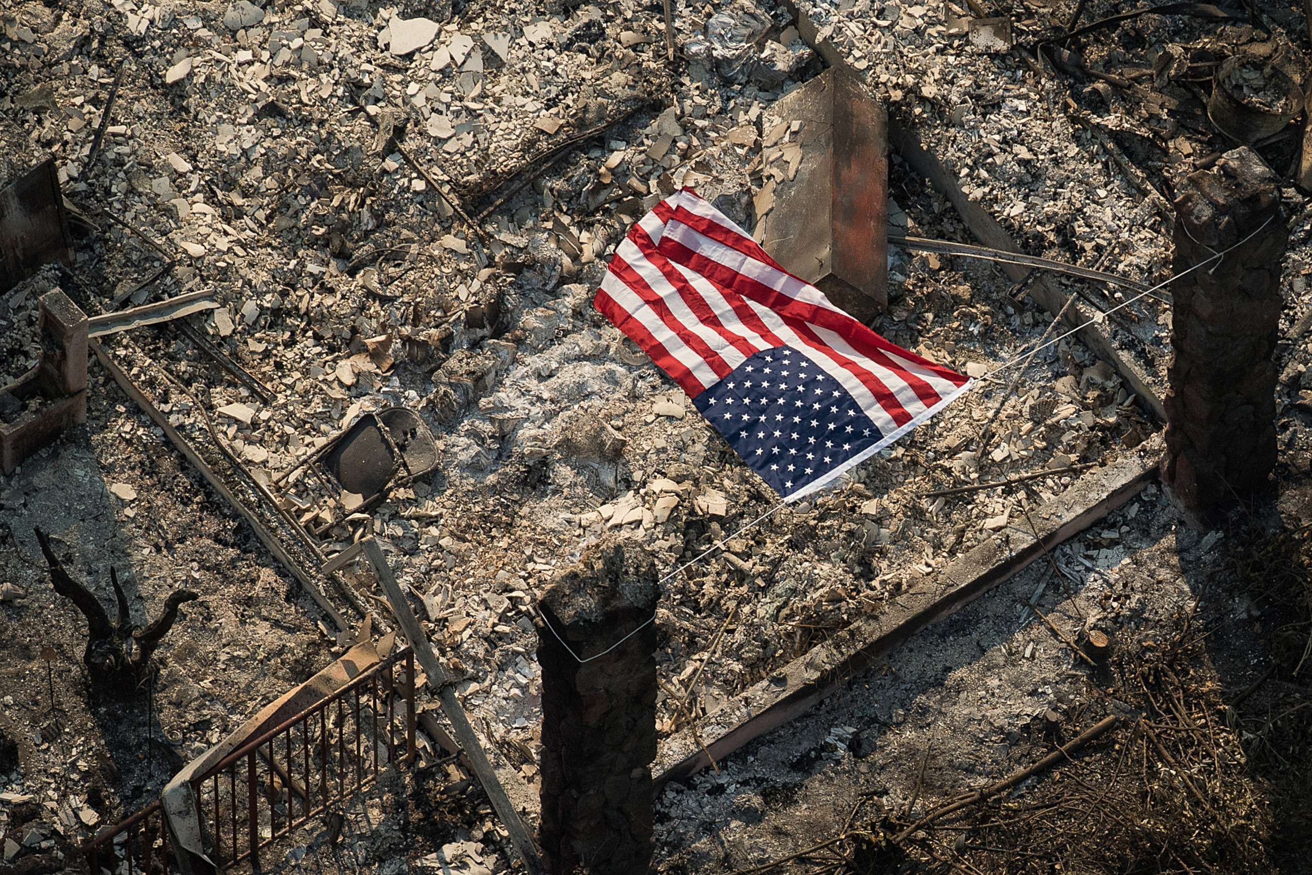 PHOTO: An American flag flies over the remains of a Coffey Park home following the Tubbs fire in Santa Rosa, Calif.