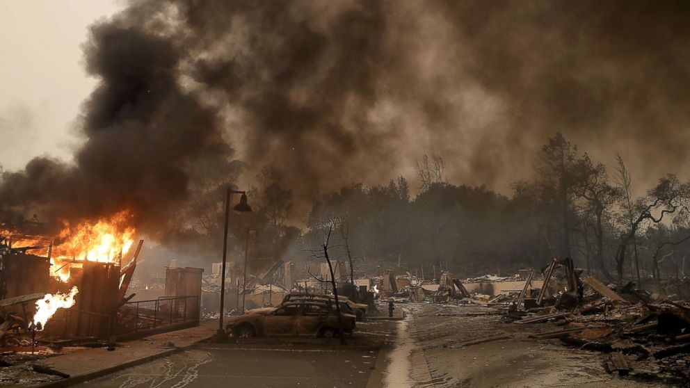 PHOTO: Burned out cars sit next to a building on fire in a fire ravaged neighborhood, Oct. 9, 2017, in Santa Rosa, Calif.