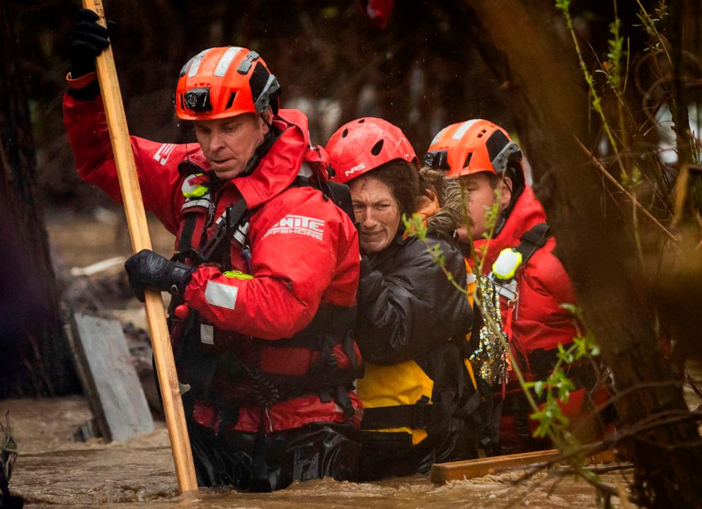 PHOTO: Firefighters rescue a woman from a homeless encampment that became surrounded by floodwater in the Santa Ana River during a rainstorm, Feb. 5, 2024, in San Bernardino, Calif. 