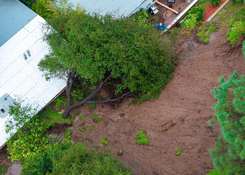 PHOTO: This aerial view shows a man shovelling mud after a landslide pushed a tree into his and his neighbor's houses, Feb. 5, 2024, in Los Angeles.