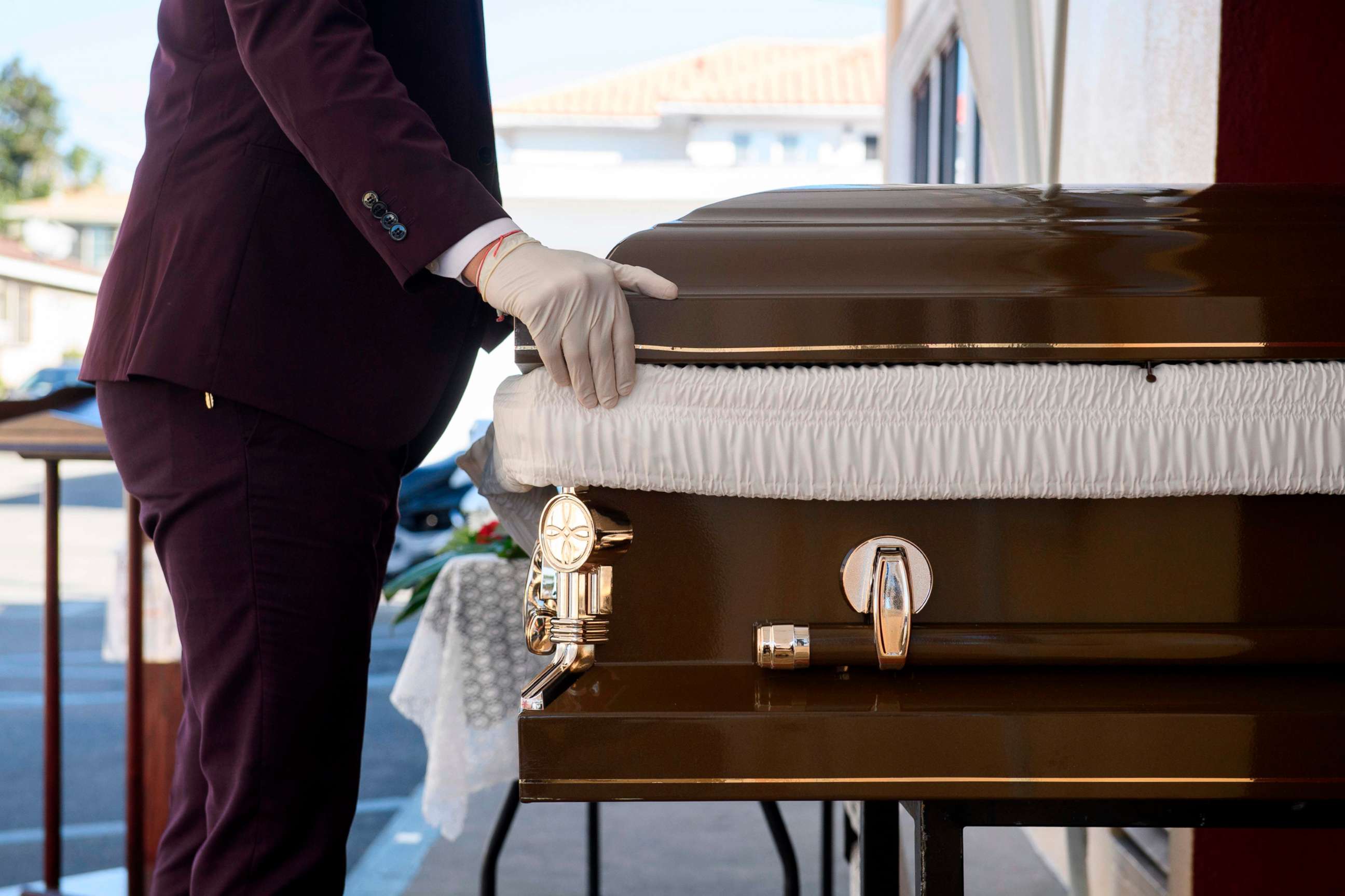 PHOTO: Funeral director Steven Correa wears gloves as he moves the casket of Gilberto Arreguin Camacho, 58, in preparation for burial following his death due to Covid-19 at Continental Funeral Home on  Dec. 31, 2020, in East Los Angeles, Calif.