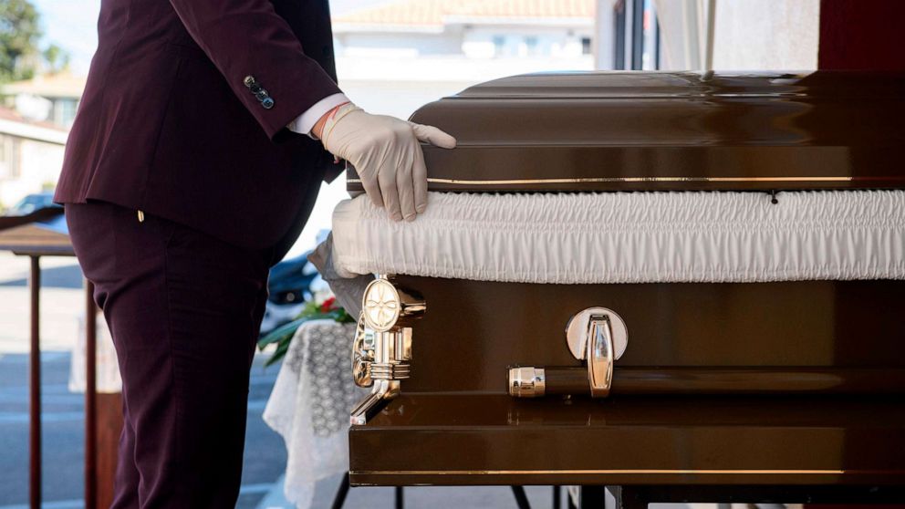 PHOTO: Funeral director Steven Correa wears gloves as he moves the casket of Gilberto Arreguin Camacho, 58, in preparation for burial following his death due to Covid-19 at Continental Funeral Home on  Dec. 31, 2020, in East Los Angeles, Calif.