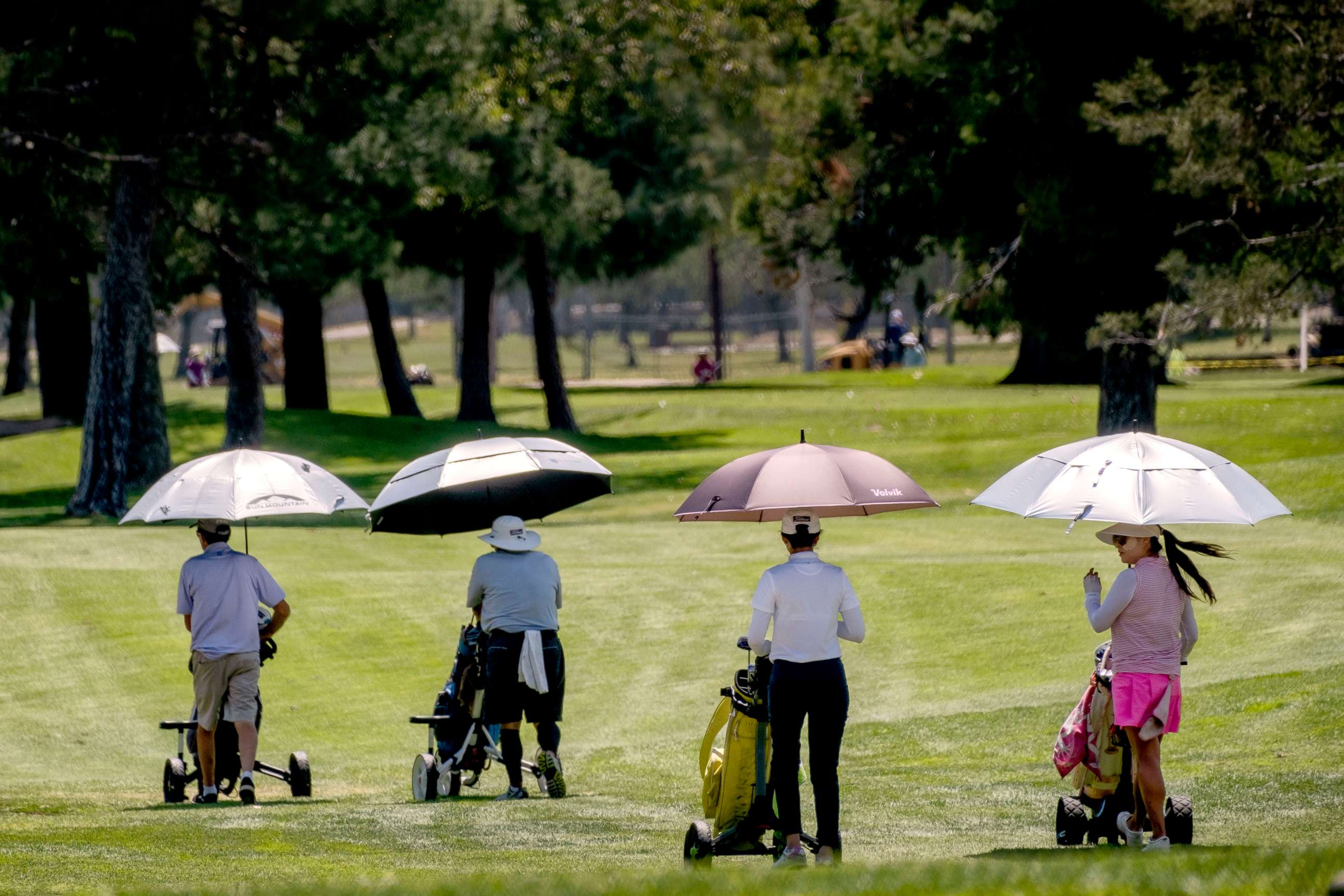 PHOTO: Golfers use umbrellas to shield them from the sun while on the links at Brookside Golf Course in Pasadena, CA, April 25, 2022.