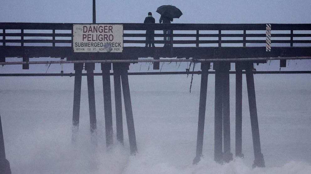 PHOTO: People stand on a pier over the Pacific Ocean with Hurricane Hilary approaching in San Diego County, Aug. 20, 2023 in Imperial Beach, Calif.