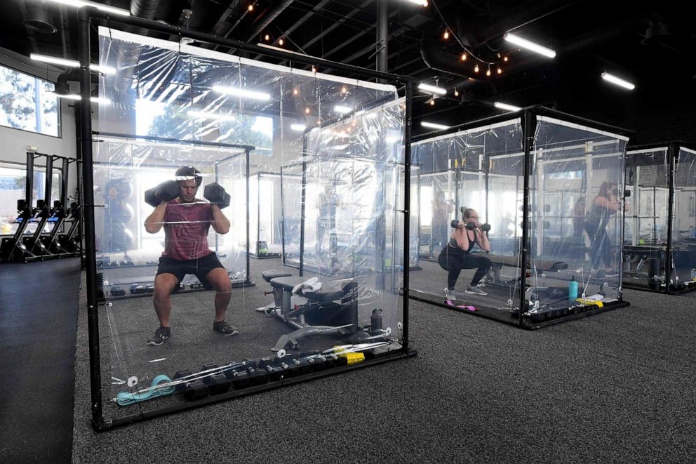 PHOTO: People exercise at Inspire South Bay Fitness behind plastic sheets in their workout pods while observing social distancing, June 15, 2020, in Redondo Beach, California, as the gym reopens under California's coronavirus Phase 3 reopening guidelines.