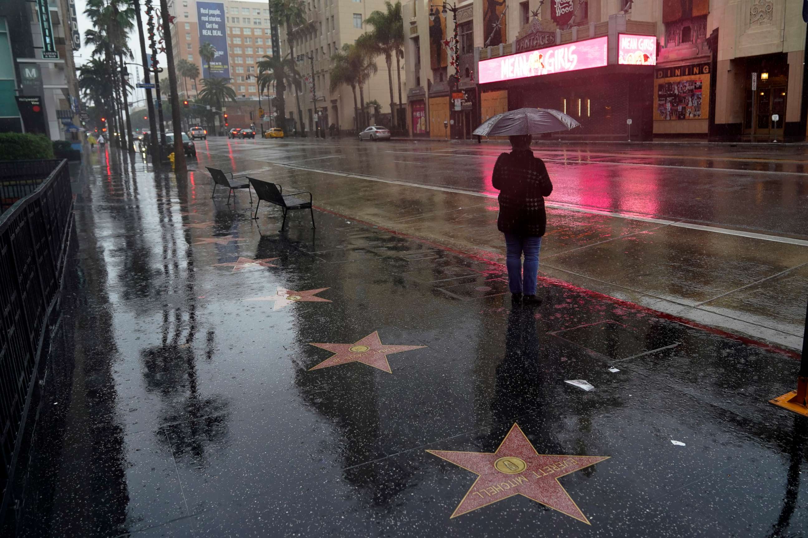 PHOTO: A woman waits at a bus stop in the rain on Dec. 28, 2020, in the Hollywood section of Los Angeles.