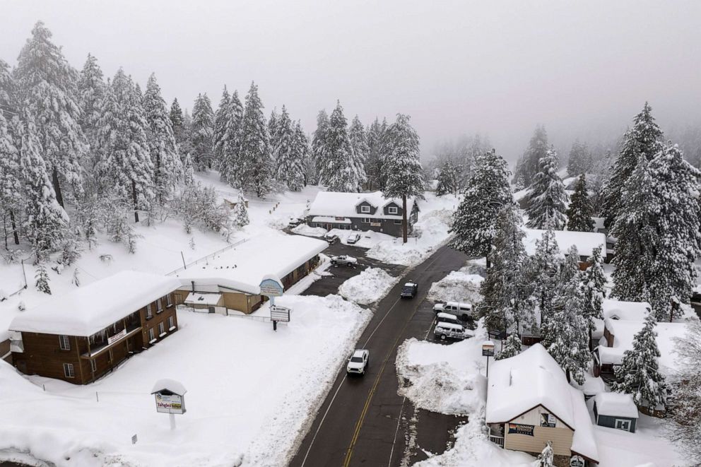 PHOTO: Motorists drive past snow-covered buildings in Running Springs, Calif., Feb. 28, 2023.