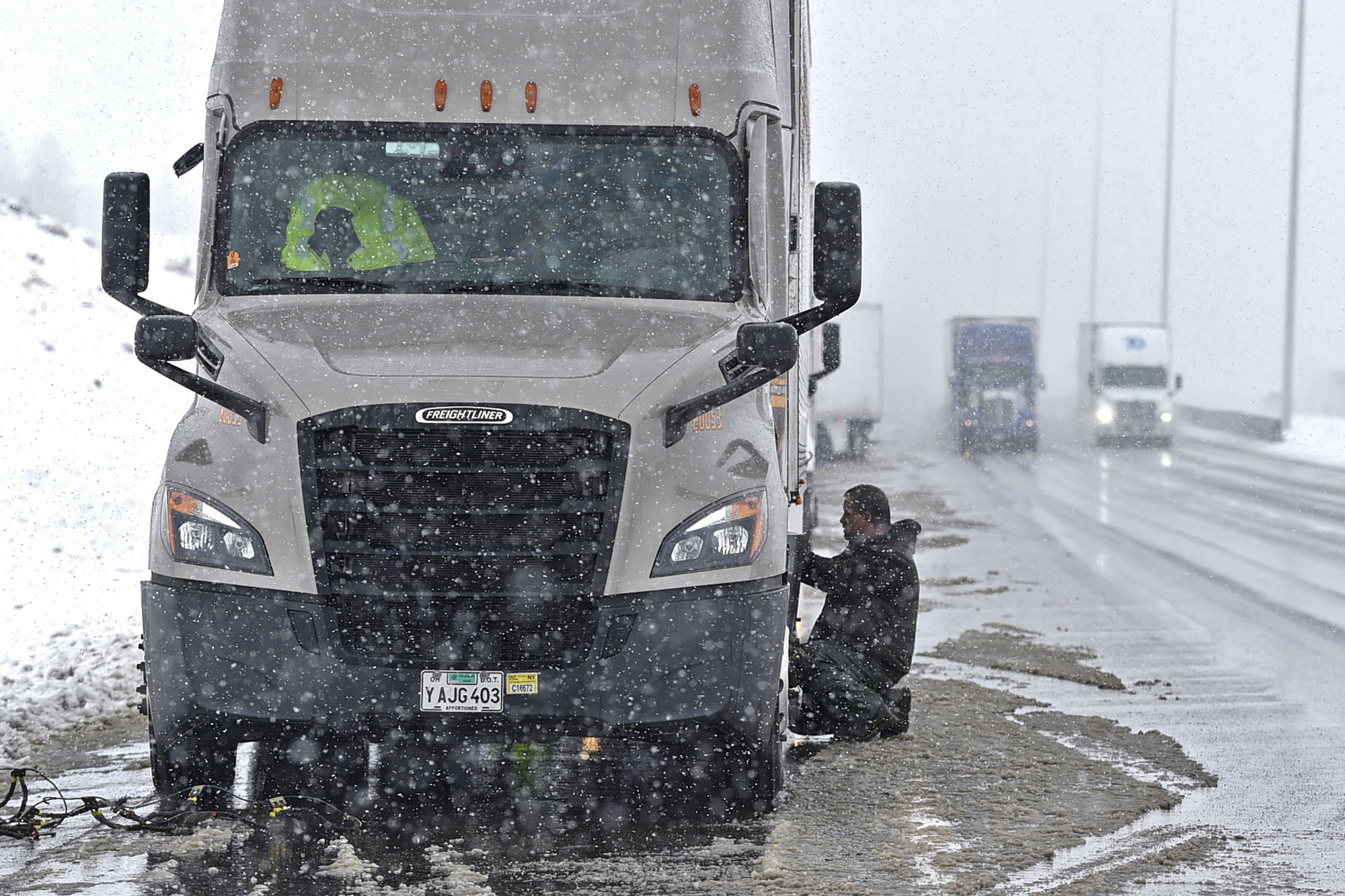 PHOTO: Truck drivers pull over on the west bound I-80 just outside of Reno, Nev., to install chains on their trucks on Jan. 28, 2021. A storm brought rains to California on Thursday as blizzard conditions buried the Sierra Nevada in snow. 