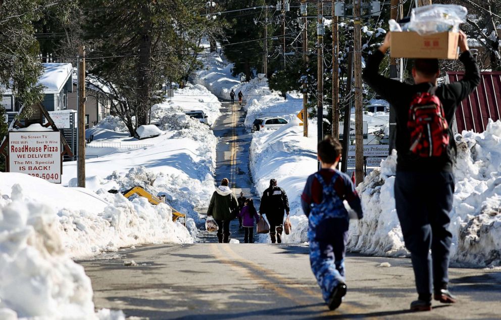 PHOTO: People carry donated food after a series of winter storms dumped heavy snowfall in the San Bernardino Mountains in Southern California, March 3, 2023 in Crestline, Calif.
