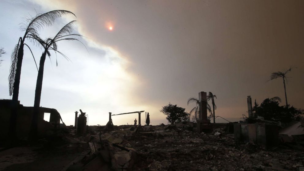 PHOTO: A man walks among the ruins of a home destroyed by the Thomas Fire as smoke obscures the sky in Ventura, Calif., Dec. 6, 2017.