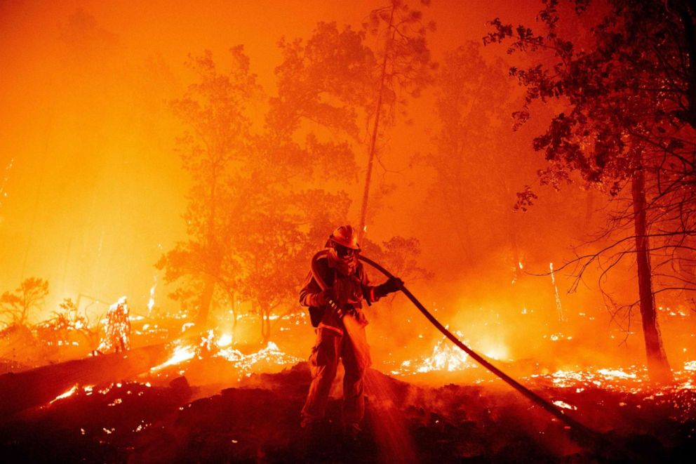 PHOTO: In this Sept. 7, 2020, file photo, a firefighter douses flames as they push towards homes during the Creek fire in the Cascadel Woods area of Madera County, Calif.