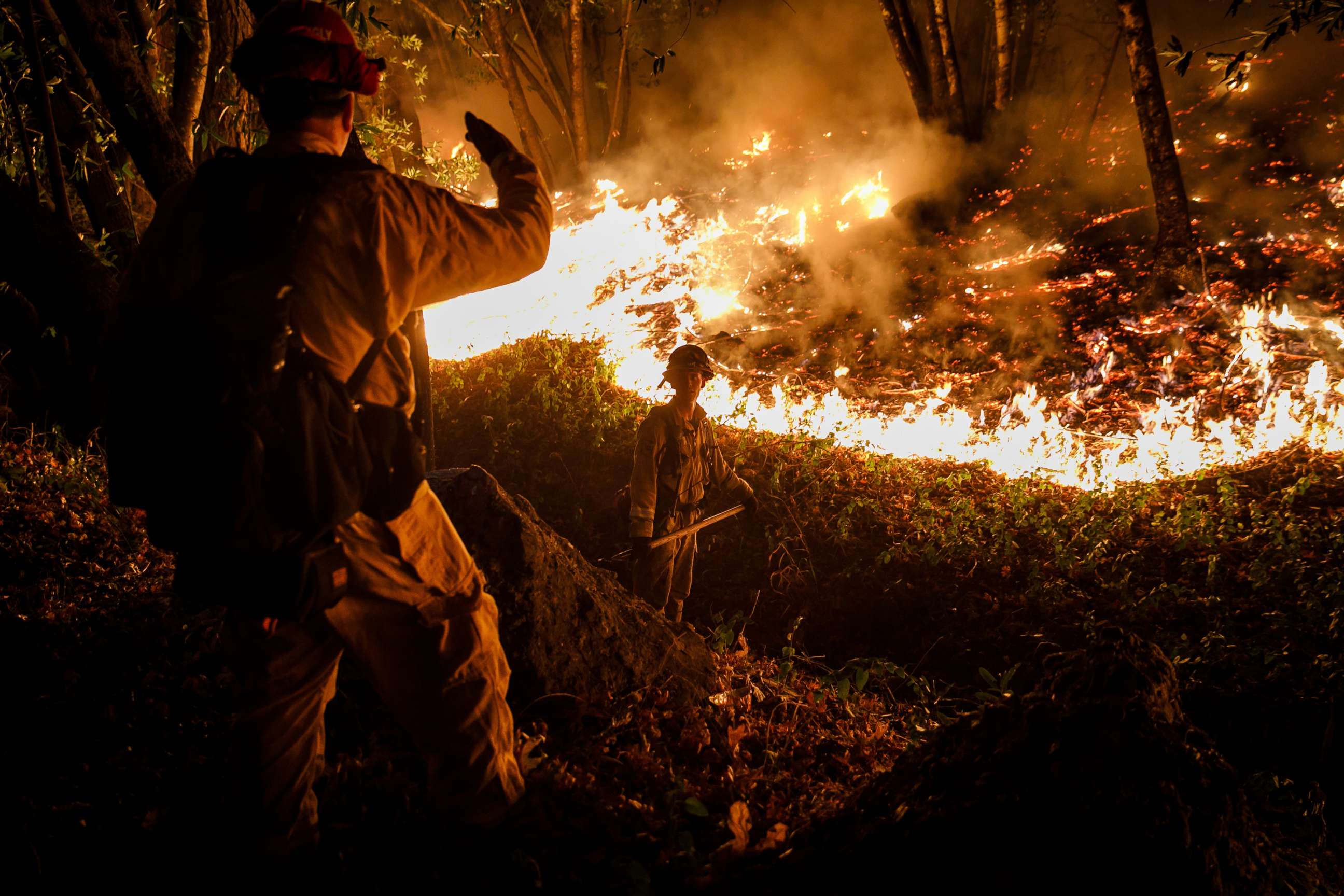 PHOTO: CALFIRE firefighter Tim Zanotelli, center, receives instructions from Captain Gary Mattingly, left, while performing a firing operation to prevent the flames from crossing Highway 29, north of Calistoga, Calif., Oct. 12, 2017. 