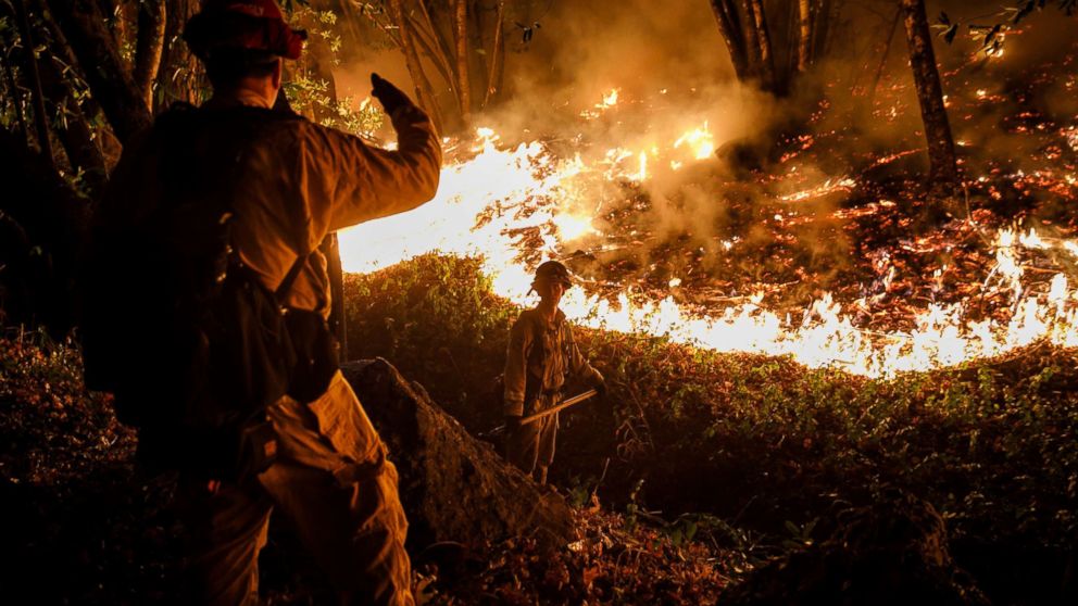 CALFIRE firefighter Tim Zanotelli, center, receives instructions from Captain Gary Mattingly, left, while performing a firing operation to prevent the flames from crossing Highway 29, north of Calistoga, Calif., Oct. 12, 2017.