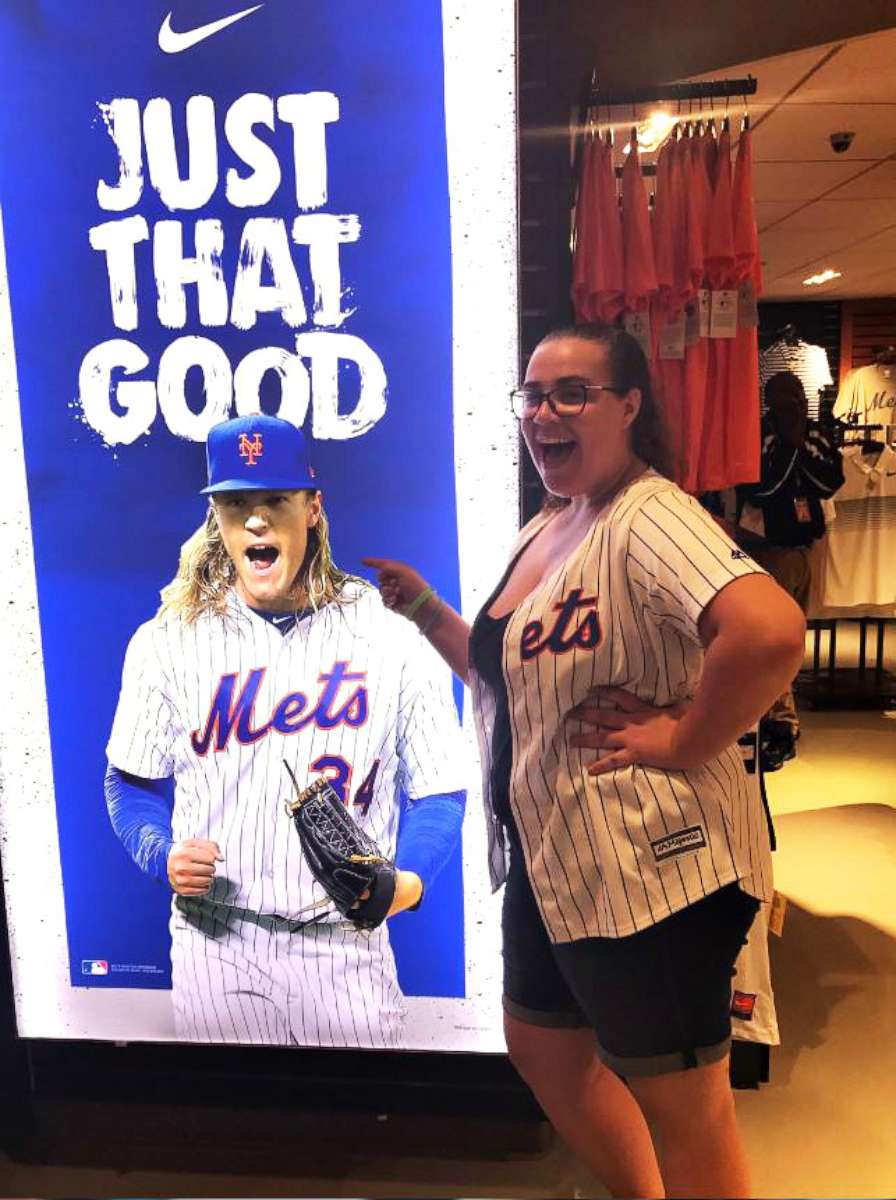 PHOTO: Callie Quinn, a high school senior and lifelong Mets fan, at a Mets gift shop points at a picture of one of her favorite team players at a Mets gift shop.