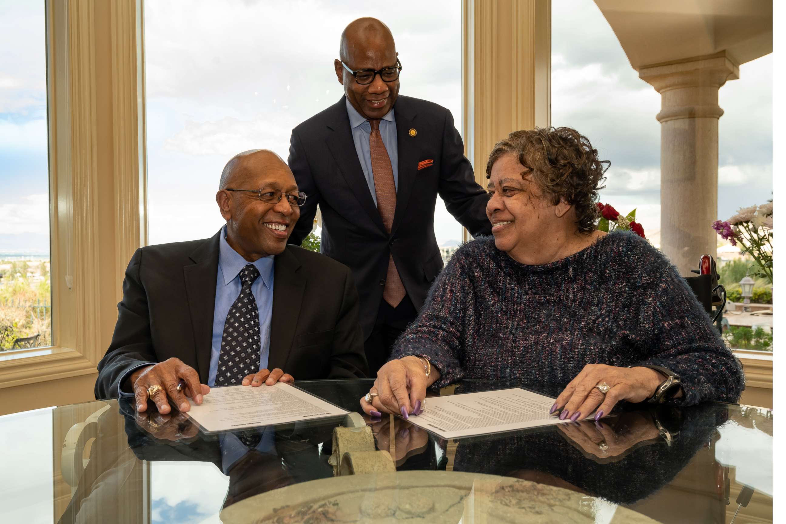 PHOTO: Calvin Tyler Jr. and his wife, Tina, smile at each other after signing a giving pledge for $20 million to Morgan State University as the university's president, David K. Wilson, looks on at the Tylers' home in Las Vegas on Feb. 20, 2021. 