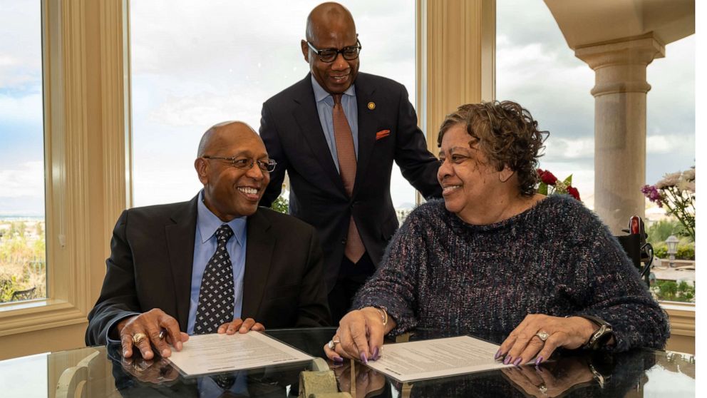 PHOTO: Calvin Tyler Jr. and his wife, Tina, smile at each other after signing a giving pledge for $20 million to Morgan State University as the university's president, David K. Wilson, looks on at the Tylers' home in Las Vegas on Feb. 20, 2021. 