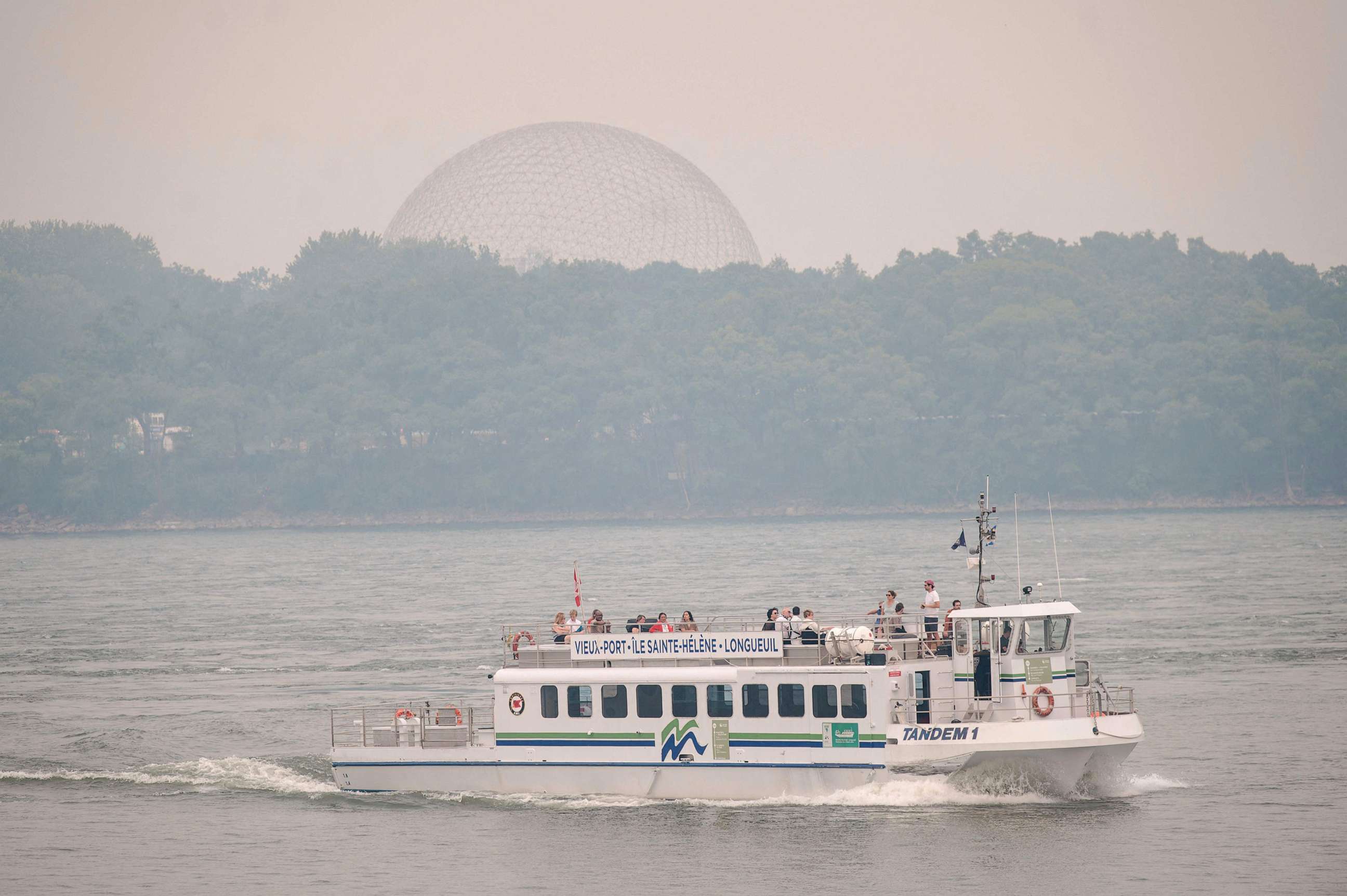 PHOTO: A tourist boat passes on the St. Lawrence river as the Biosphere is seen through the smoke filled skies caused by the wildfires in Northern Quebec in Montreal, Quebec, on June 25, 2023.