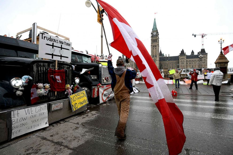 PHOTO: A protester waves the Canadian flag in front of a revving truck on Wellington Street as a protest against COVID-19 restrictions continues in Ottawa, Feb. 10, 2022.