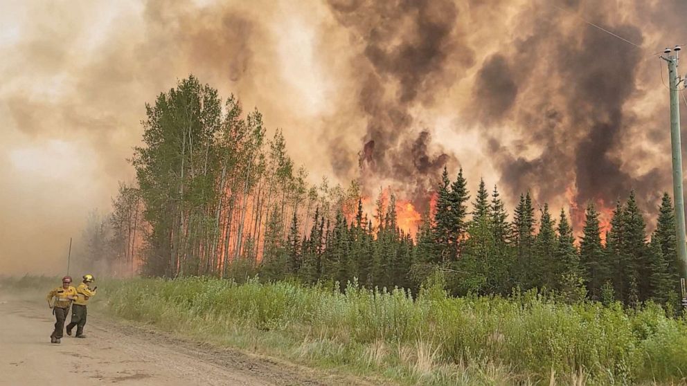 PHOTO: Firefighters retreat as flames approach, amid the Grizzly Wildfire Complex, in East Prairie Metis Settlement, Alberta, Canada, on May 19, 2023 in this still image obtained from social media video.