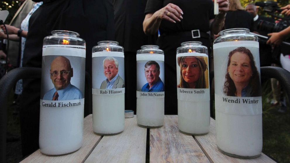 PHOTO: Photos of five journalists adorn candles during a vigil across the street from where they were slain in their newsroom in Annapolis, Md., June 29, 2018.