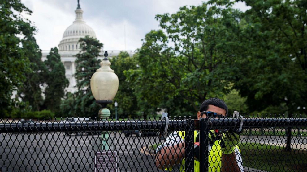 PHOTO: A worker removes bolts holding security fencing that surrounds the Capitol, July 9, 2021. 