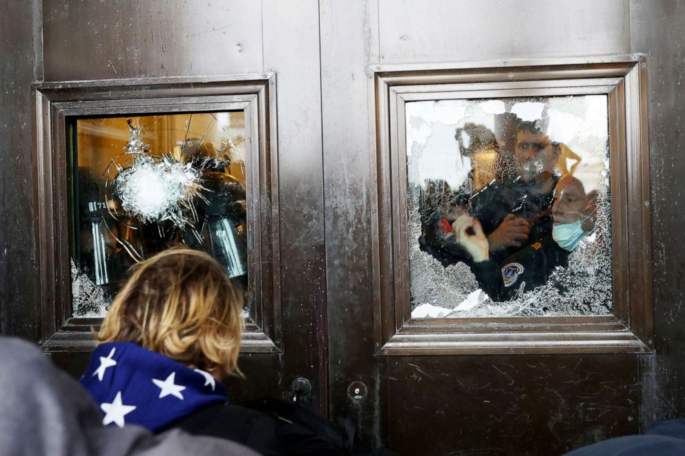 PHOTO: A Capitol police officer looks out of a broken window as protesters gather on the U.S. Capitol Building, Jan. 06, 2021. 
