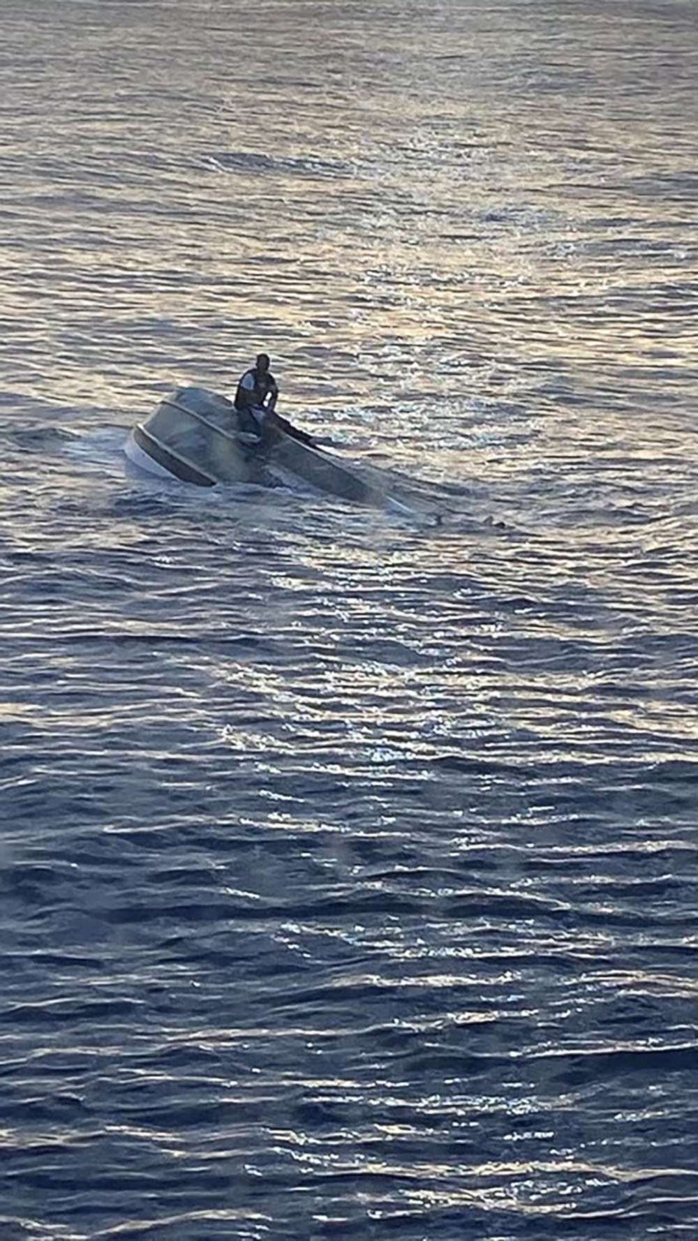 PHOTO: A man, who says he was one of 40 people who left Bimini, Bahamas, on Saturday before encountering severe weather, sits on a capsized boat off the coast of Fort Pierce Inlet, Florida, Jan. 25, 2022.