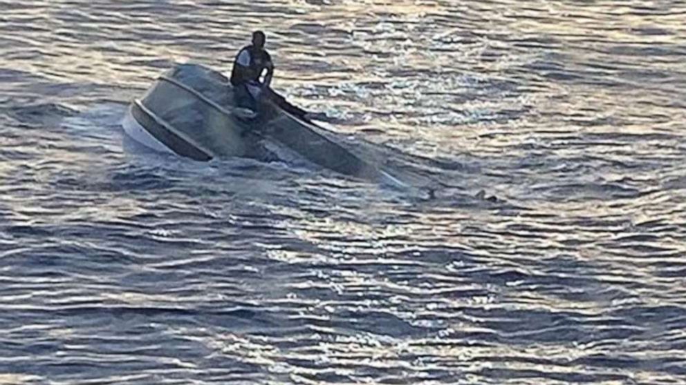 PHOTO: A man, who says he was one of 40 people who left Bimini, Bahamas, on Saturday before encountering severe weather, sits on a capsized boat off the coast of Fort Pierce Inlet, Florida, Jan. 25, 2022.
