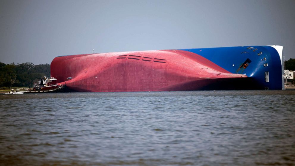 PHOTO: A Moran tugboat nears the stern of the vessel Golden Ray as it lays on its side as a tent and rescuers can be seen near the bottom of the ship near the tug boat, Monday, Sept. 9, 2019, in Jekyll Island, Ga.