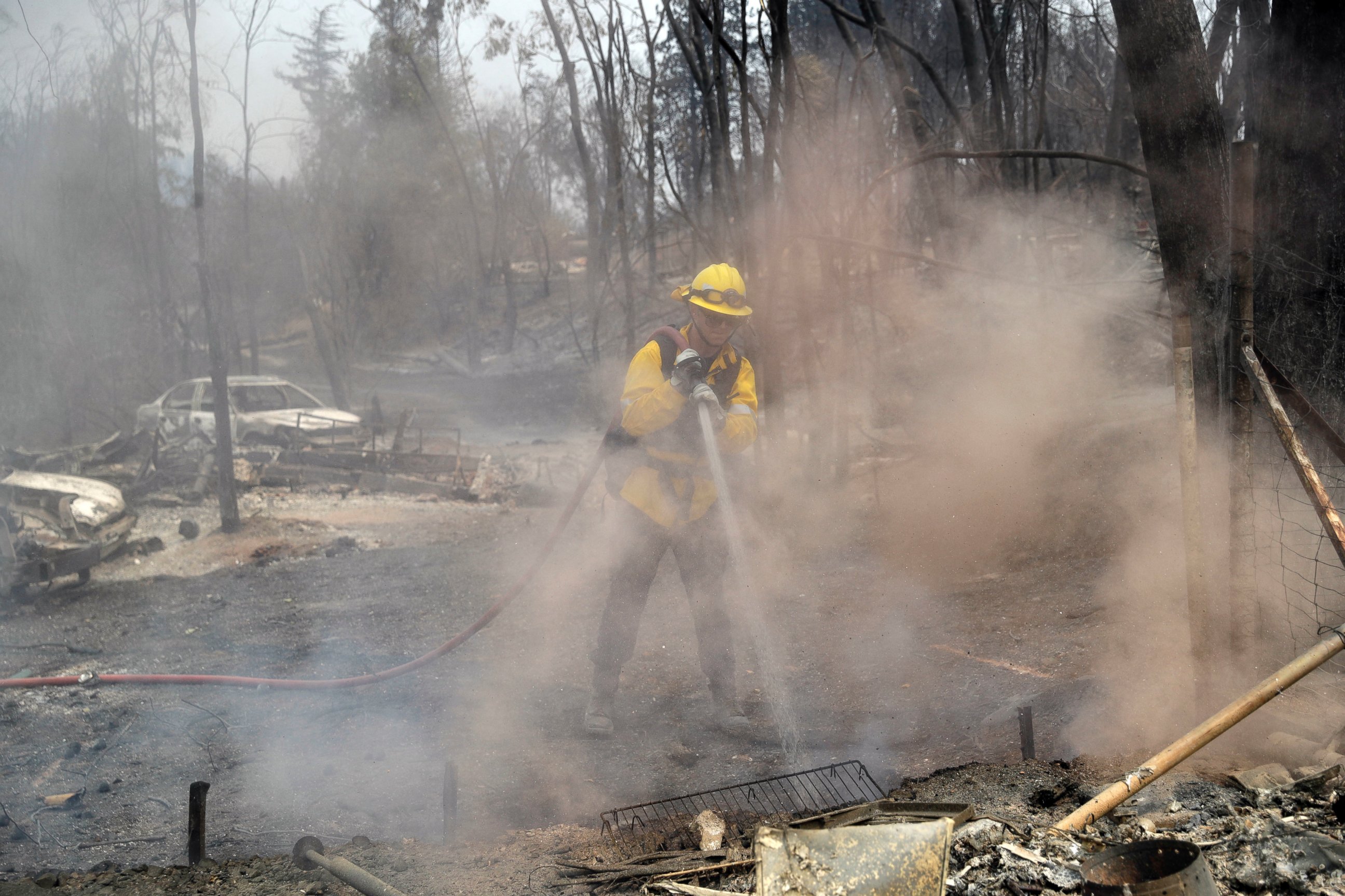San Bernardino County Fire Department firefighter James Lippen hoses down hot spots left behind by a wildfire, Sunday, July 29, 2018, in Keswick, Calif.