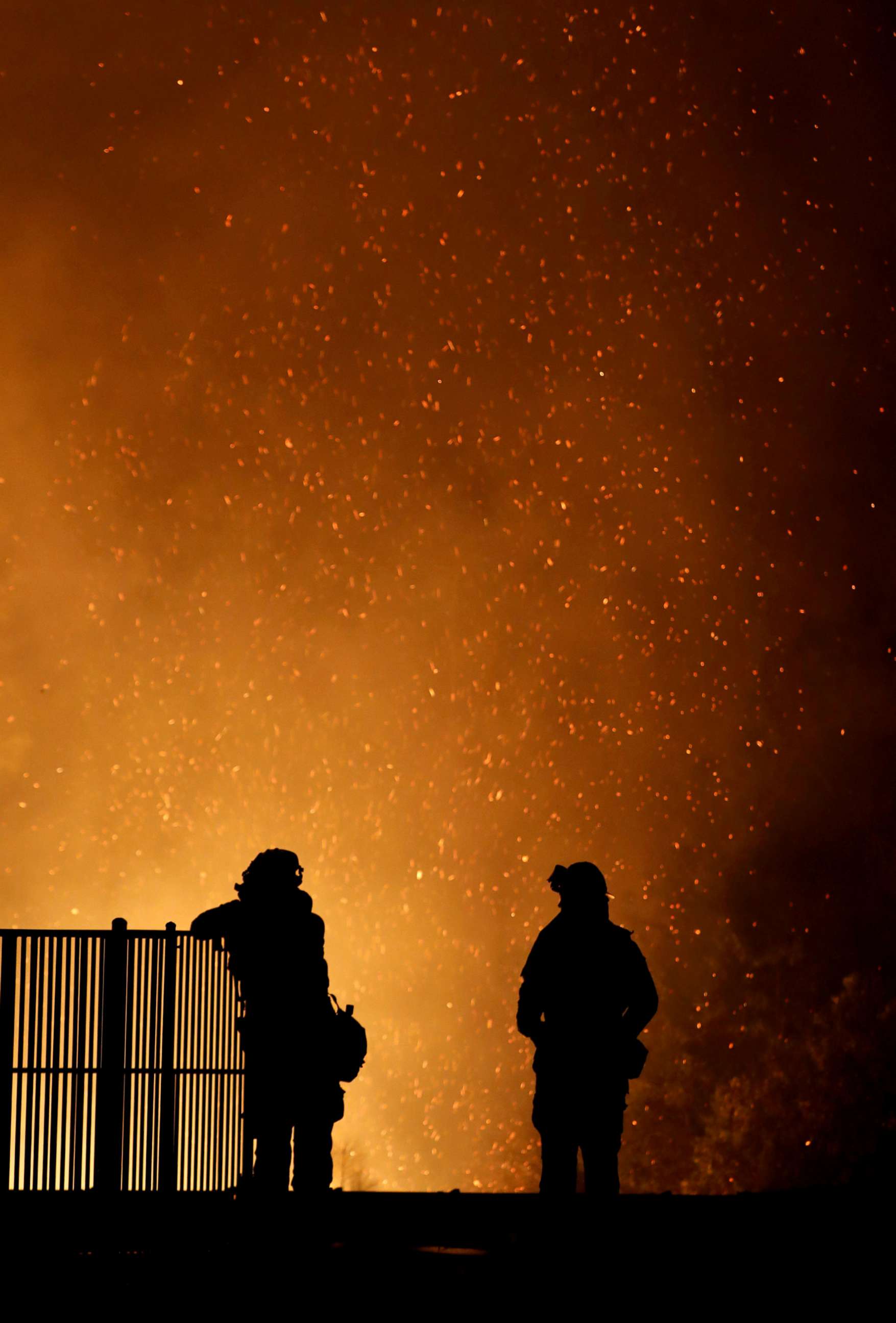 PHOTO: Burning embers swirl around firefighters as they stand guard at a home while battling the Carr Fire, west of Redding, Calif., July 27, 2018.