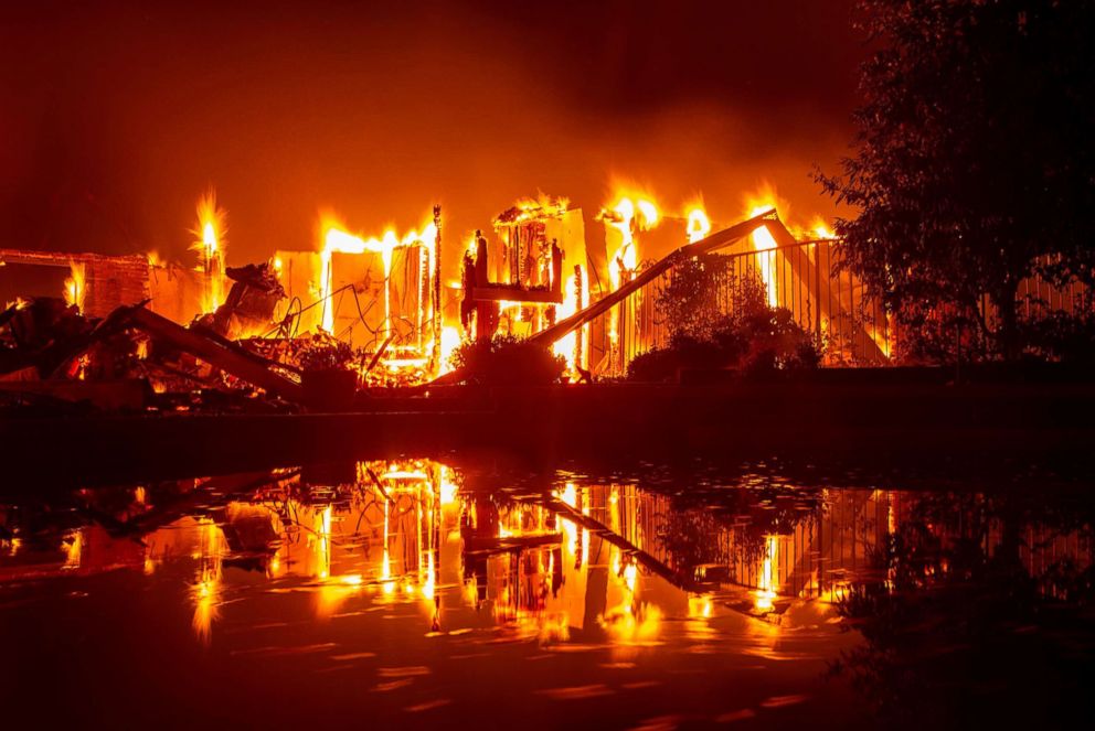 PHOTO: A burning home is reflected in a pool during the Carr fire in Redding, Calif., July 27, 2018.
