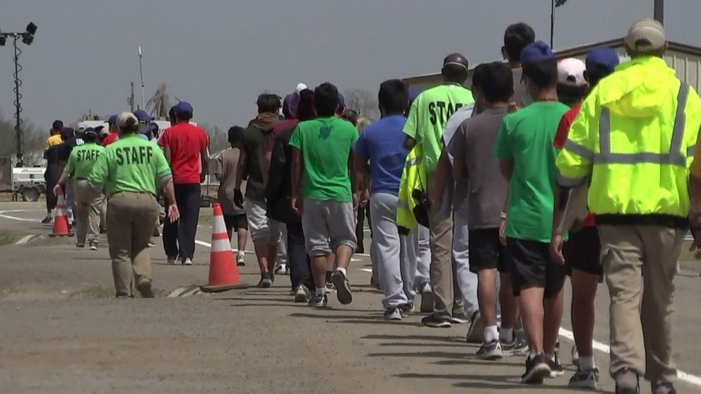 PHOTO: Unaccompanied immigrant children walk surrounded by staff members through the Carrizo Springs Influx Care Facility in Carrizo Springs, Texas, March 24, 2021.