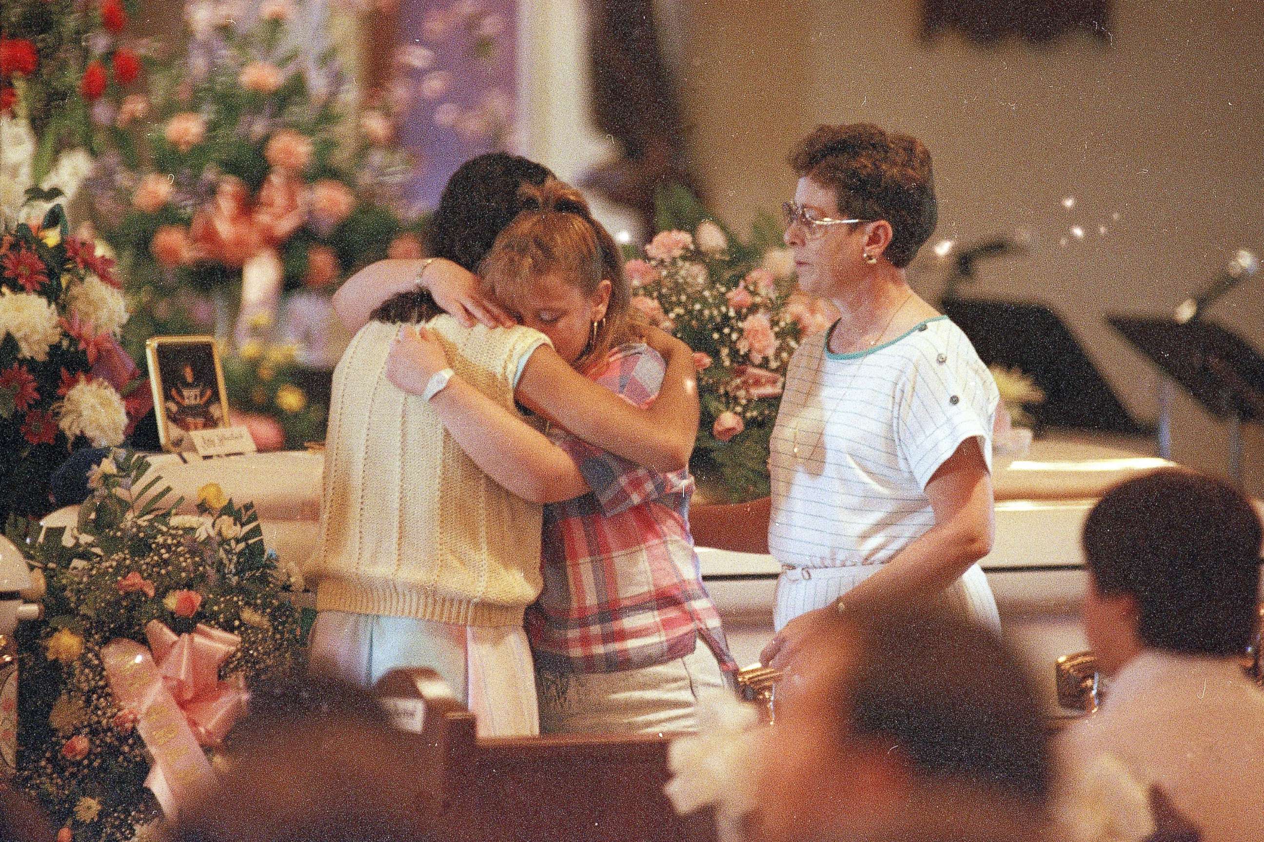 PHOTO: Two young women embrace each other as they stand in front of the casket of Amy Christine Wheelock during her funeral Mass at St. Christopher Church in Radcliff, Ky., May 18, 1988.